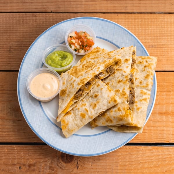 Beef quesadillas with melted cheese, served with guacamole, salsa, and a creamy sauce.